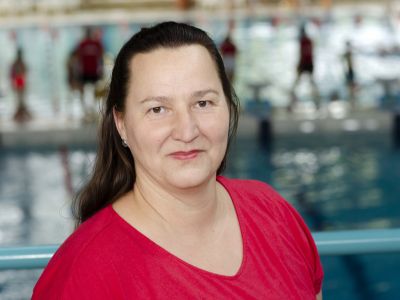 Trainerin Katja Hollnick im roten T-Shirt. Im Hintergrund ein Schwimmbecken.