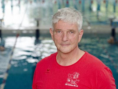 Trainer Uwe Sachse im roten T-Shirt. Im Hintergrund ein Schwimmbecken.