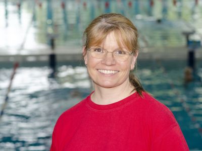 Trainerin Sylvia Drews im roten T-Shirt. Im Hintergrund ein Schwimmbecken.