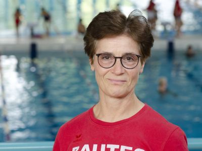 Trainerin Carmen Loecke im roten T-Shirt. Im Hintergrund ein Schwimmbecken.