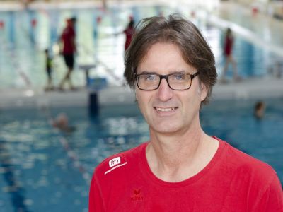 Trainer Mario Oy im roten T-Shirt. Im Hintergrund ein Schwimmbecken.